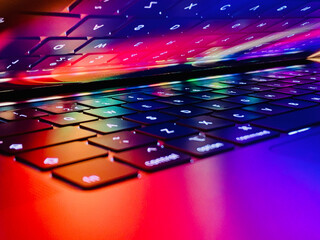 Vibrant MacBook closeup of lights reflecting on the keyboard and trackpad from the colourful screen