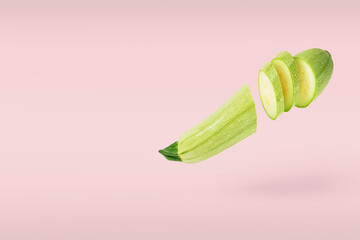 Singl vegetable marrow raw fresh sliced several parts small flying on pink background. Concept levitation food. Copy space for text.