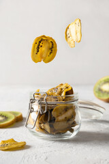 Kiwi chips glying to glass gar for storage and eating on light background, home drying. Vegan free...