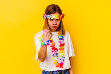Young caucasian woman celebrating a hawaiian party isolated on yellow background showing fist to...