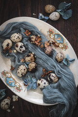 Natural quail eggs on a plate with dried flowers, shot from above. Natural Easter decoration