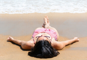 Beautiful girl sunbathes lying on the sandy seashore.
