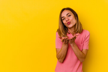 Young caucasian skinny woman isolated on yellow background folding lips and holding palms to send air kiss.