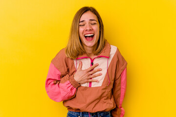 Young caucasian skinny woman isolated on yellow background laughs out loudly keeping hand on chest.