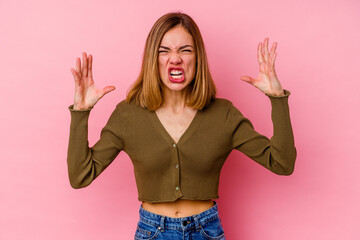 Young caucasian woman isolated on pink background screaming with rage.