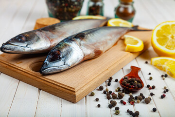 Raw mackerel on a cutting board with spices.