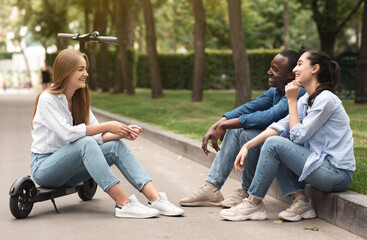 Three happy friends spending time in park and talking