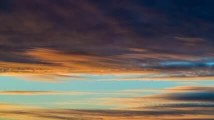 Dark colored clouds in blue sky at sunset 