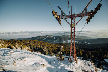 A man beside a ski lift in the mountains with dogs