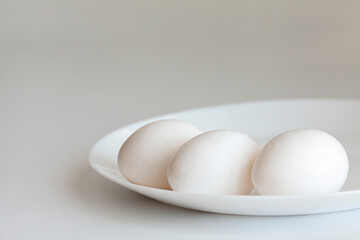 White eggs on a white plate on a white background close up. Easter breakfast concept. 