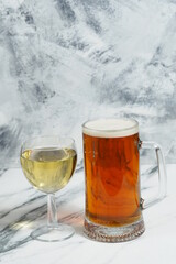 On a light background - a mug of beer and a glass of white wine. Alcoholic beverages. Wine or beer to choose from. Bar card.