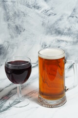 On a light background is a mug of beer, and a glass of red wine. Alcoholic beverages. Wine or beer to choose from. Bar card.