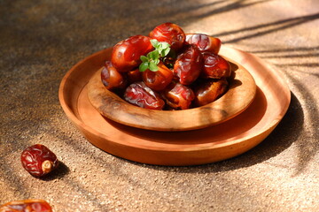 dates fruit in a wooden plate against brown background
