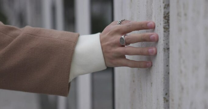 Close up of a beautiful man hand with rings driving along a modern and beautiful building wall of stone and glass, touching, senses, 4k slowmotion