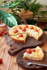 Tart with cheese, tomatoes and fish. Side view.