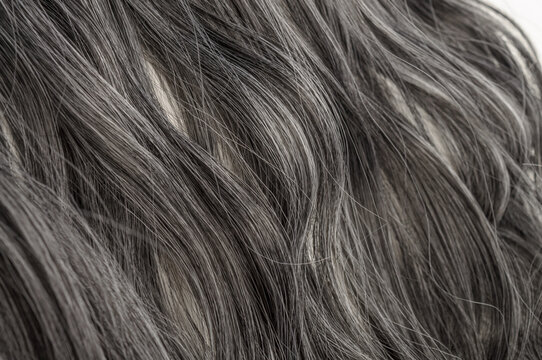 closeup texture of single piece of clip in wavy black mixed with grey highlights synthetic hair extensions