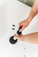 Plumber unclogging bathtub with professional force pump cleaner.
