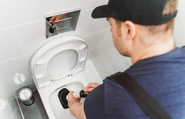 Plumber unclogging toilet with professional force pump cleaner.