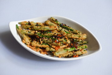a plate of fried crispy green beans served with chili flakes in white background