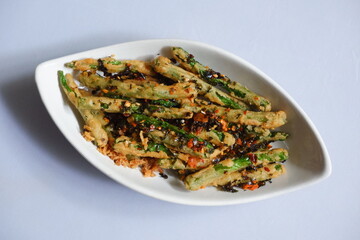 a plate of fried crispy green beans served with chili flakes in white background