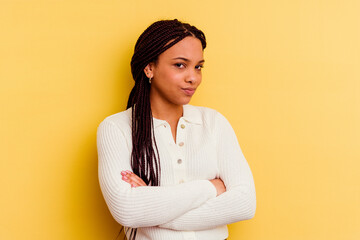 Young african american woman isolated on yellow background suspicious, uncertain, examining you.
