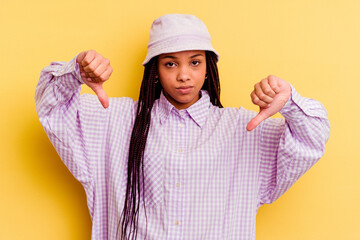 Young african american woman isolated on yellow background showing a dislike gesture, thumbs down....