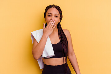 Young sport african american woman holding a towel isolated on yellow background yawning showing a tired gesture covering mouth with hand.