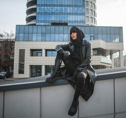 Woman in long leather coat spy agent on background of modern building of a business center