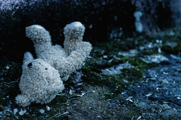 Lost childhood concept. Dirty teddy bear lying down outdoors. Copy space for text or design....