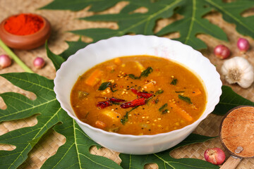 Sambar , Lentil sambar mixed vegetable curry soup for Onam sadhya vishu spicy hot isolated on green banana leaf. popular south Indian food in Kerala Tamil Nadu Sri lanka