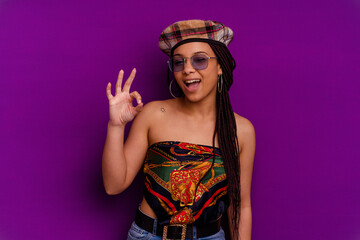 Young african american woman isolated on yellow background Young african american woman isolated on yellow background winks an eye and holds an okay gesture with hand.