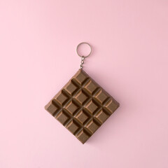 Chocolate as a key ring. Chocolate cube. Pink wallpaper. Minimal idea.