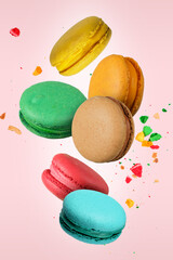 Colorful French macaroons falling or flying in motion on a light pink background