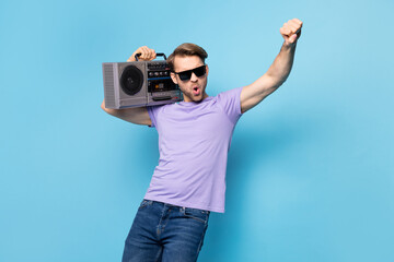 Photo of crazy excited person carry boom box on shoulder raise arm fist chilling isolated on blue color background