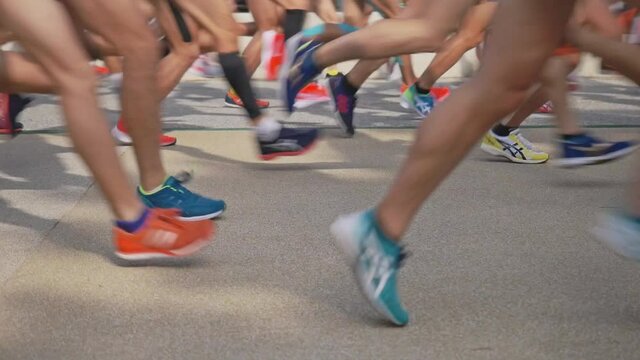 Many marathon runners running fast, leg shot
