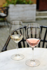 Two glasses of white and rose wine on a table in a restaurant. Summer holiday. Celebrate and enjoy moment. Alcoholic drink tasting. Romantic evening aperitif. Wine glass close up