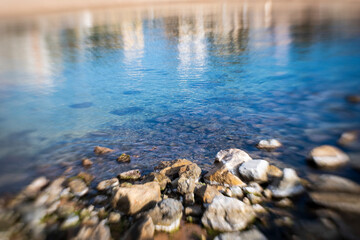 Fototapeta na wymiar Shore rocks landscape on quiet blurry blue sea waters seascape