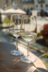 Two glasses of white wine in the sun on a table in a restaurant. Summer holiday. Celebrate and enjoy moment. Alcoholic drink tasting. Romantic evening aperitif. Wine glass close up