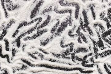 Pile of semolina with abstract pattern on a black baking sheet background