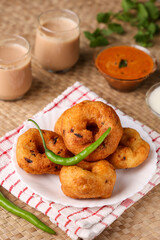 Medu Vada with tiffin sambar coconut chutney in traditional background , savory fried tea time snack of Kerala, Tamil Nadu South India. Top view of Indian veg breakfast food.