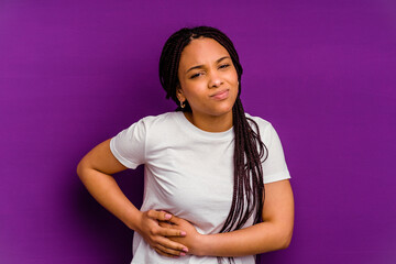 Young african american woman isolated on yellow background having a liver pain, stomach ache.