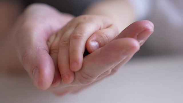 mom holds the hand of a newborn. close-up baby hand. hospital caring happy family medicine concept. baby newborn holding mom hand close-up. mom takes care of indoor the baby in the hospital