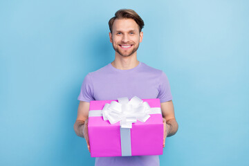 Photo portrait of smiling man keeping wrapped gift isolated on pastel blue color background
