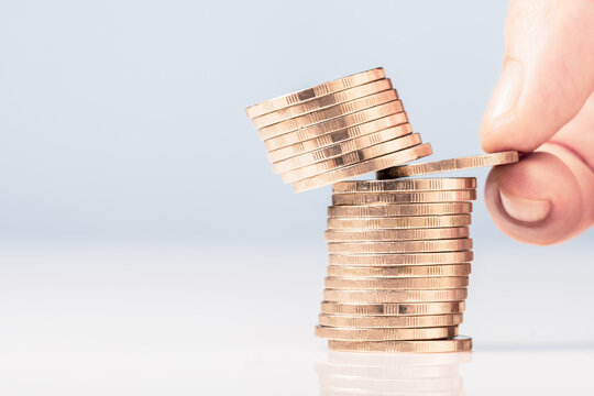 Closeup hand try to pull out a coin in the heap and risk to make the coins above crash down, business dicision, risk investment