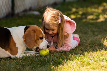 Child playing with dog on grass.