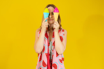 Young blonde woman wearing swimsuit and beach towel holding two ice creams