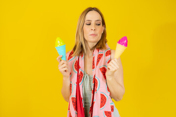 Happy woman wearing swimsuit and beach towel holding two ice creams