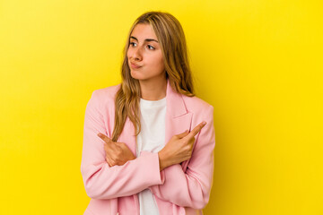 Obraz premium Young blonde caucasian woman isolated on yellow background points sideways, is trying to choose between two options.