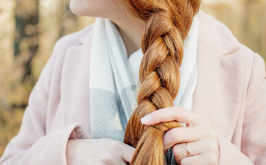 A young girl with red hair, makes her hair, collects her hair so as not to interfere.Beautiful...