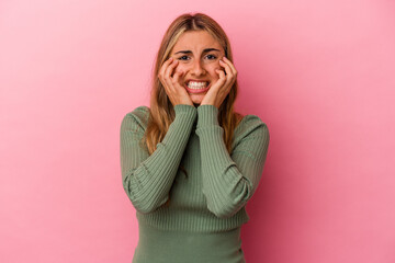 Young blonde caucasian woman isolated on pink background crying, unhappy with something, agony and confusion concept.